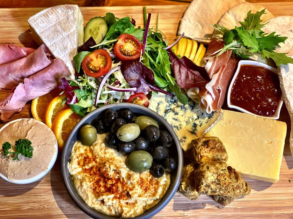A platter of salad, cheese, hummus, olives and bread